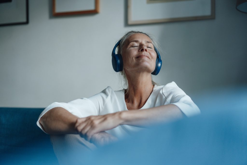 Smiling woman listening music through headphones at home