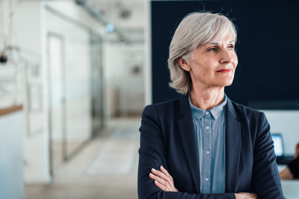Thoughtful businesswoman with arms crossed at workplace